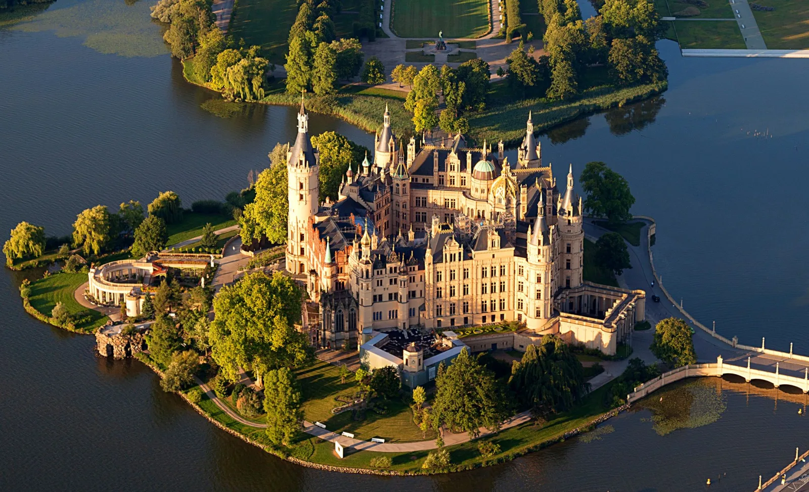 Castelo de Schwerin à beira do lago, com torres refletidas na água e céu aberto.