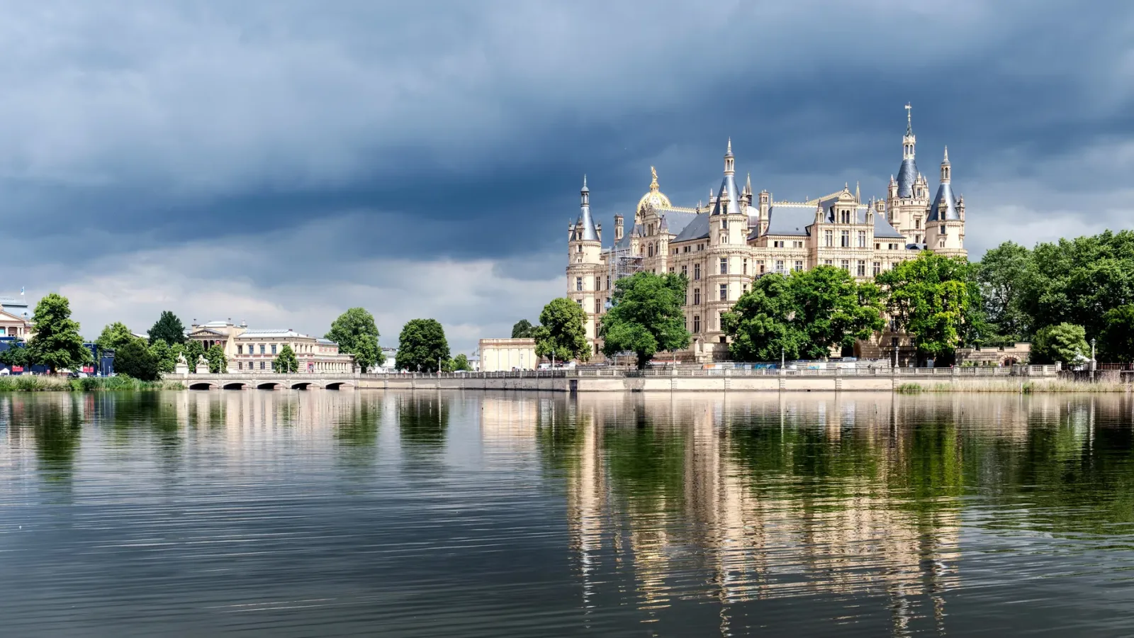 Castelo de Schwerin cercado por lago e jardins sob céu nublado