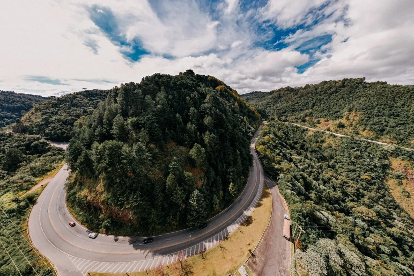 View of tree-lined streets and charming buildings in Campos do Jordão among mountains.