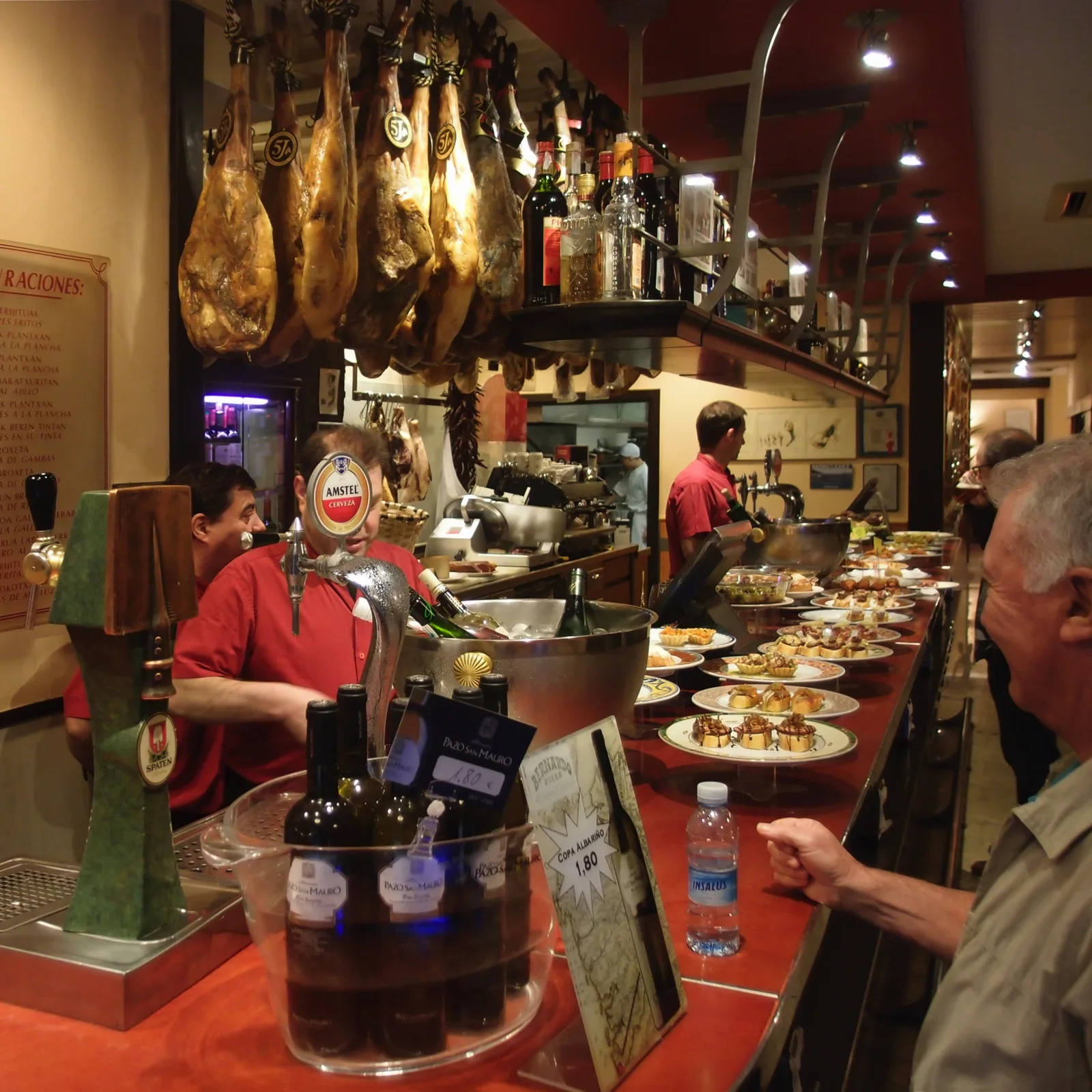Bares de pintxos animados en San Sebastián, con el mostrador lleno de tapas y clientes de pie.