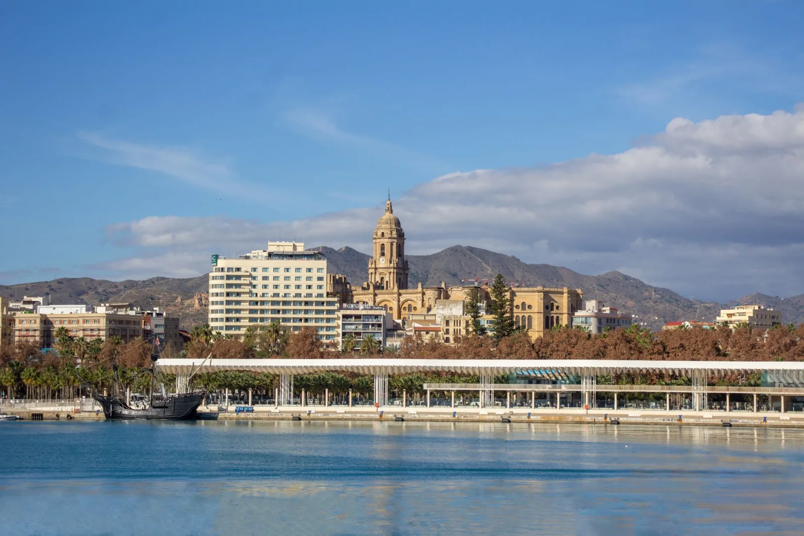 Passeio à beira do porto de Málaga, com o Muelle Uno e a praia da Malagueta ao fundo.