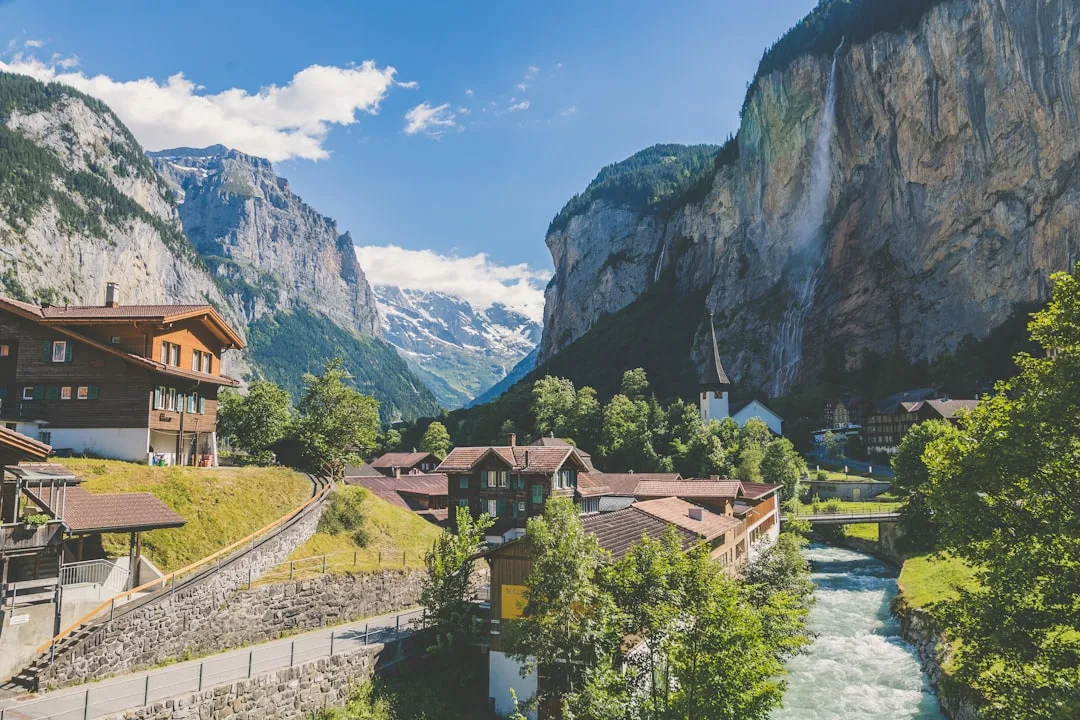 Caminho no vale de Lauterbrunnen com montanhas, chalés e cachoeiras ao fundo.
