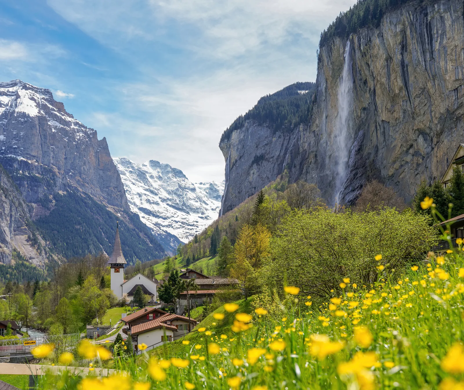 Parapentista sobrevoando o vale de Lauterbrunnen, com montanhas e vilarejo ao fundo.