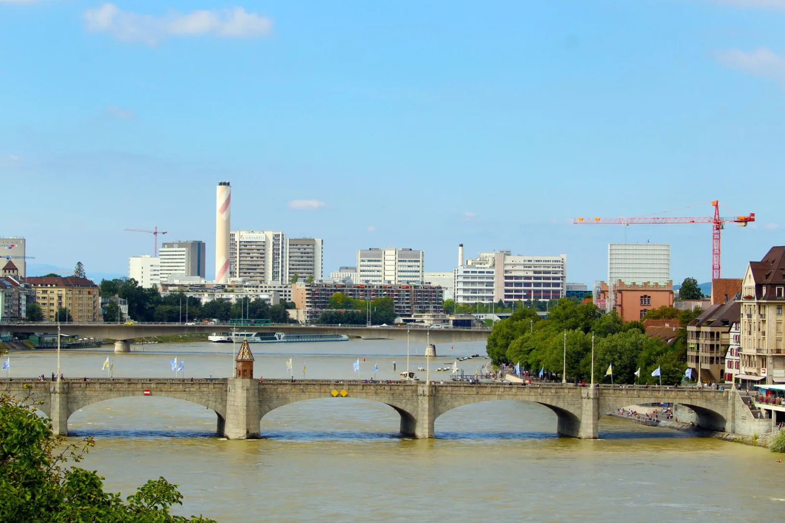 Vista urbana de Basel às margens do Reno, com arquitetura histórica e moderna.