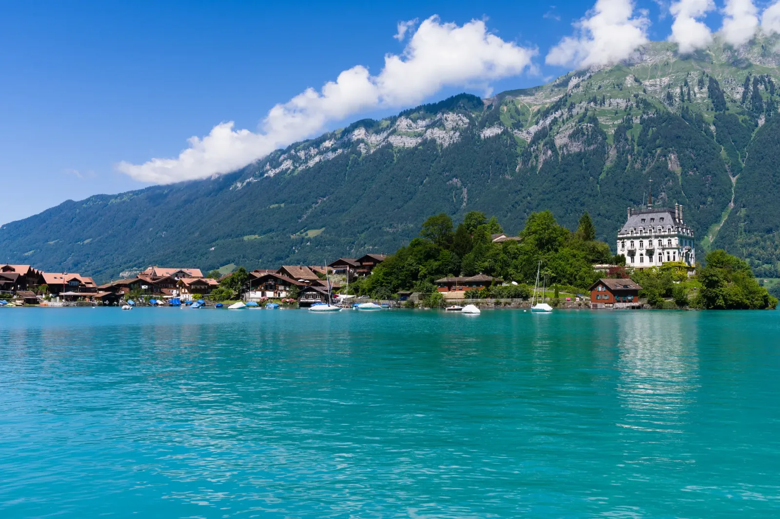 Lago de Brienz com águas azul-turquesa, vila alpina e montanhas ao fundo.