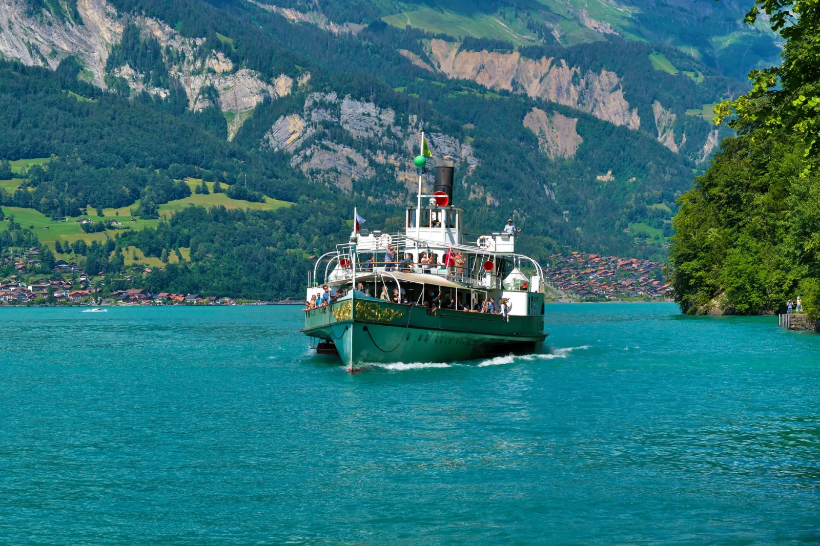 Barco cruzando as águas azul-turquesa do Lago Brienz, com montanhas ao fundo.