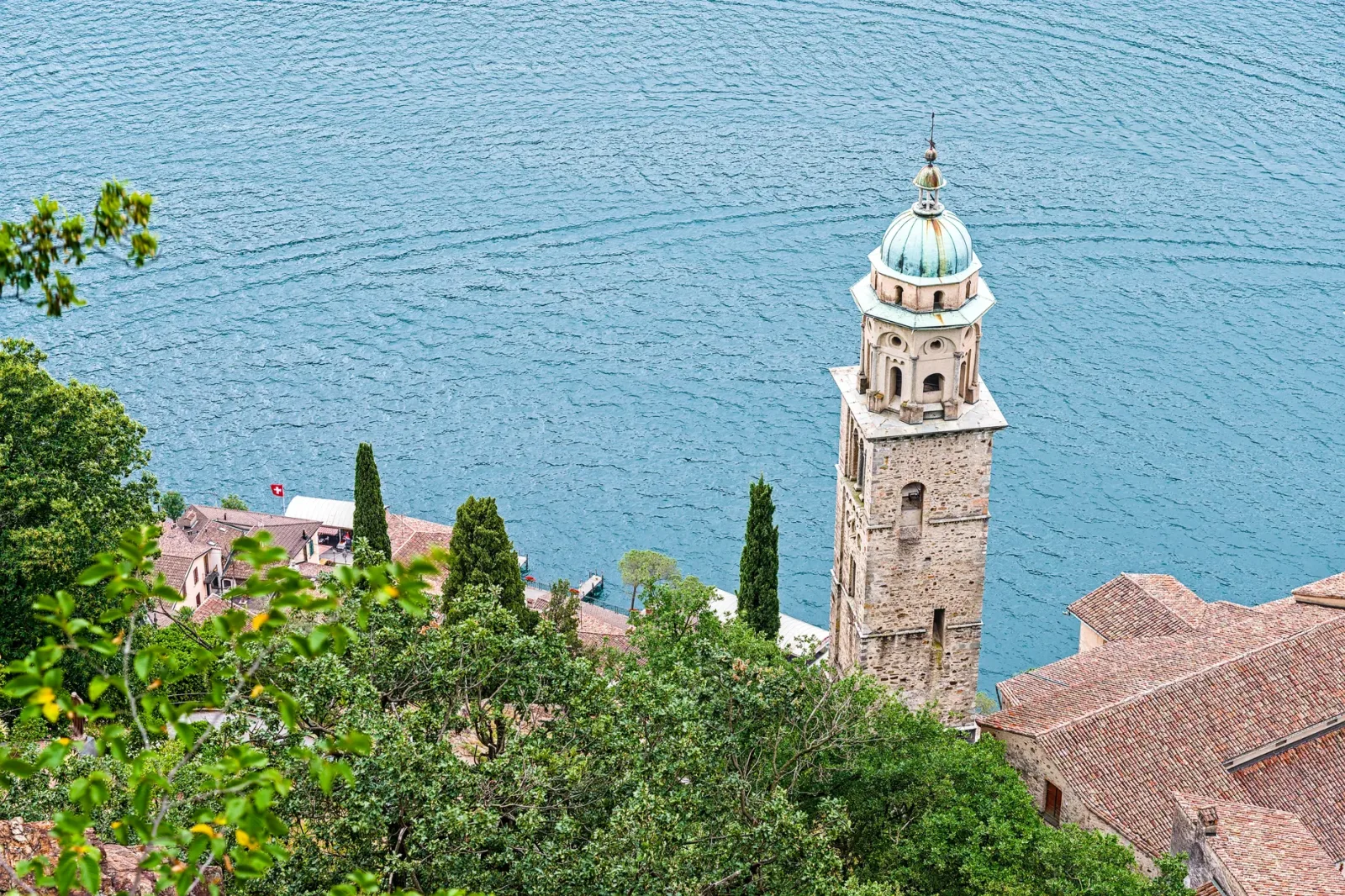 Barco no Lago de Lugano com Morcote ao fundo, cenário típico de acesso à vila.