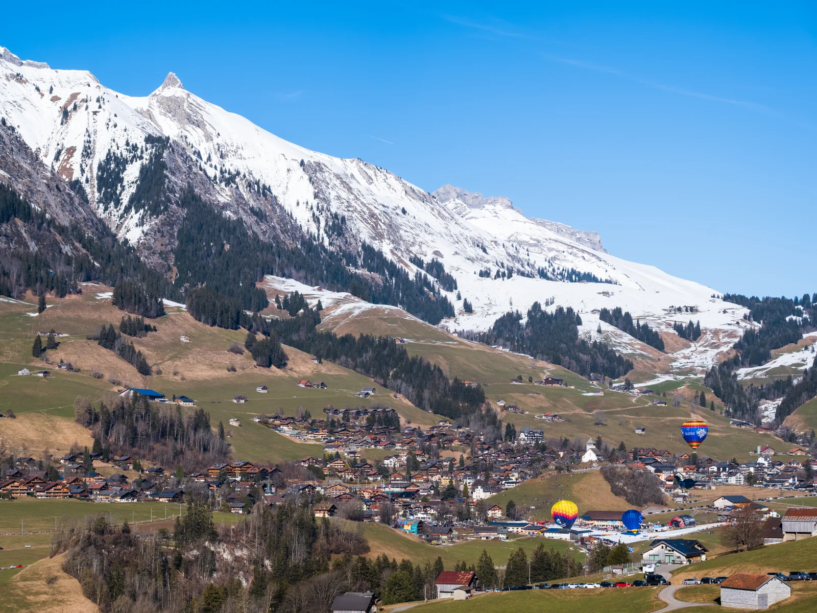 Balões coloridos sobre os Alpes em Château-d’Oex, com neve no inverno.