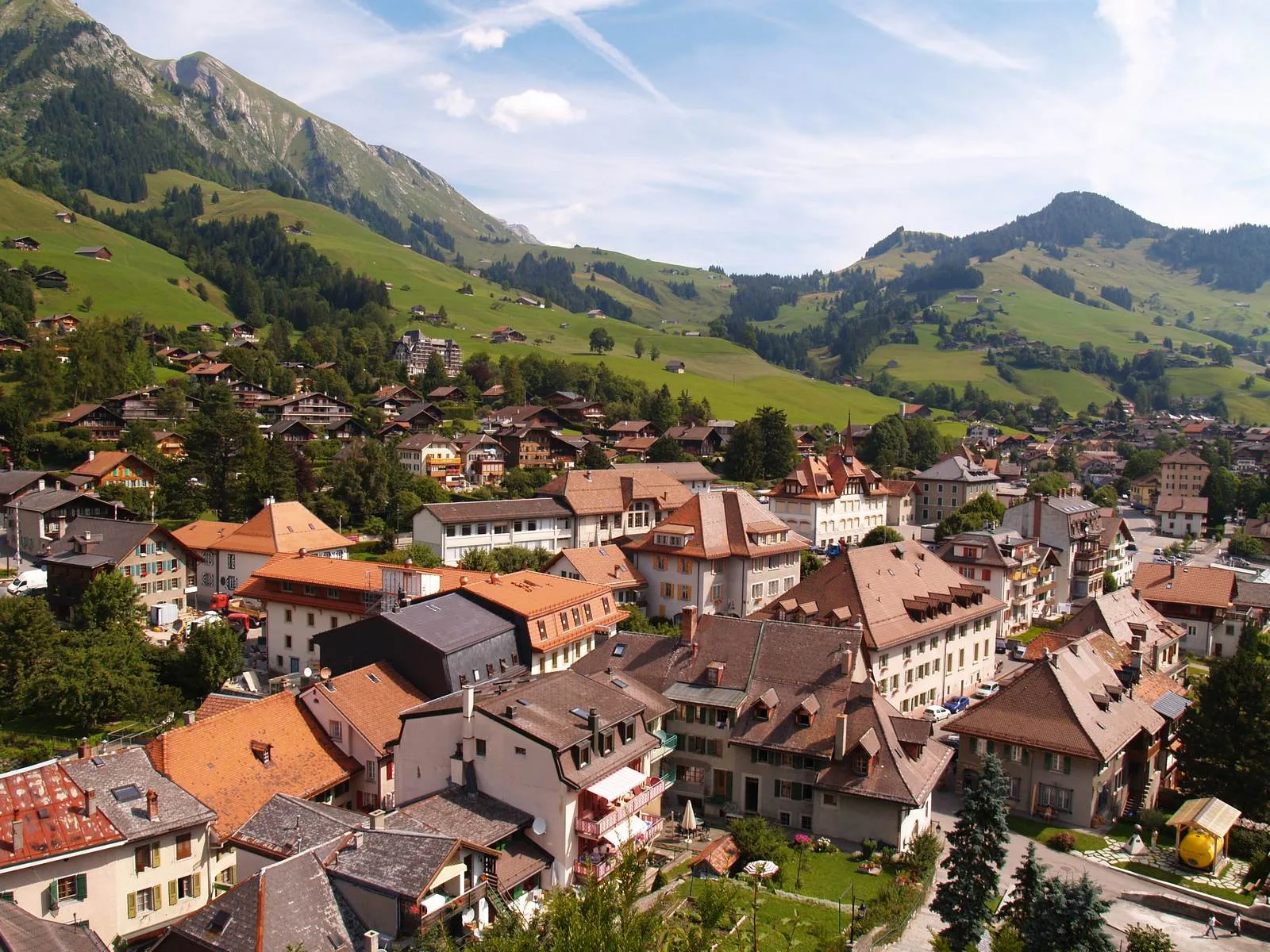 Vilarejo alpino de Saanen com casas tradicionais e montanhas ao fundo, perto de Gstaad.