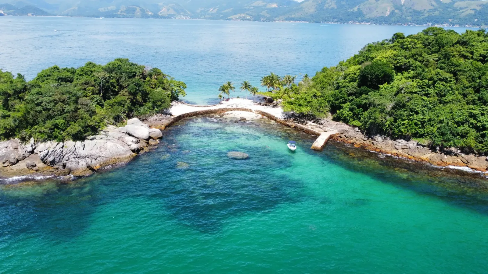 Boat sailing along the coast of Angra dos Reis, with islands and green sea in the background.