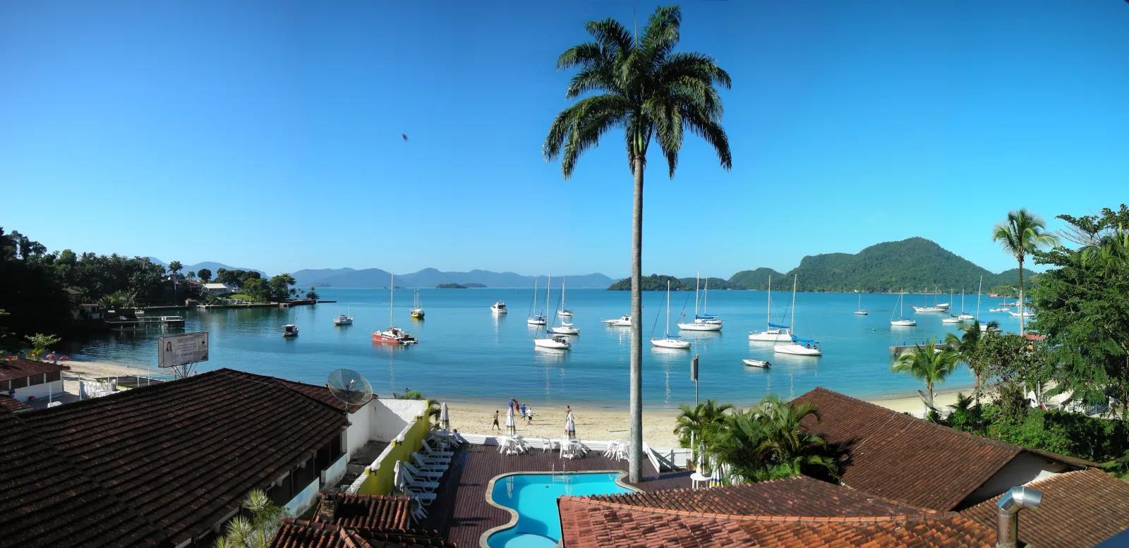 Clear-water beach in Angra dos Reis, with white sand and a sea surrounded by green hills.