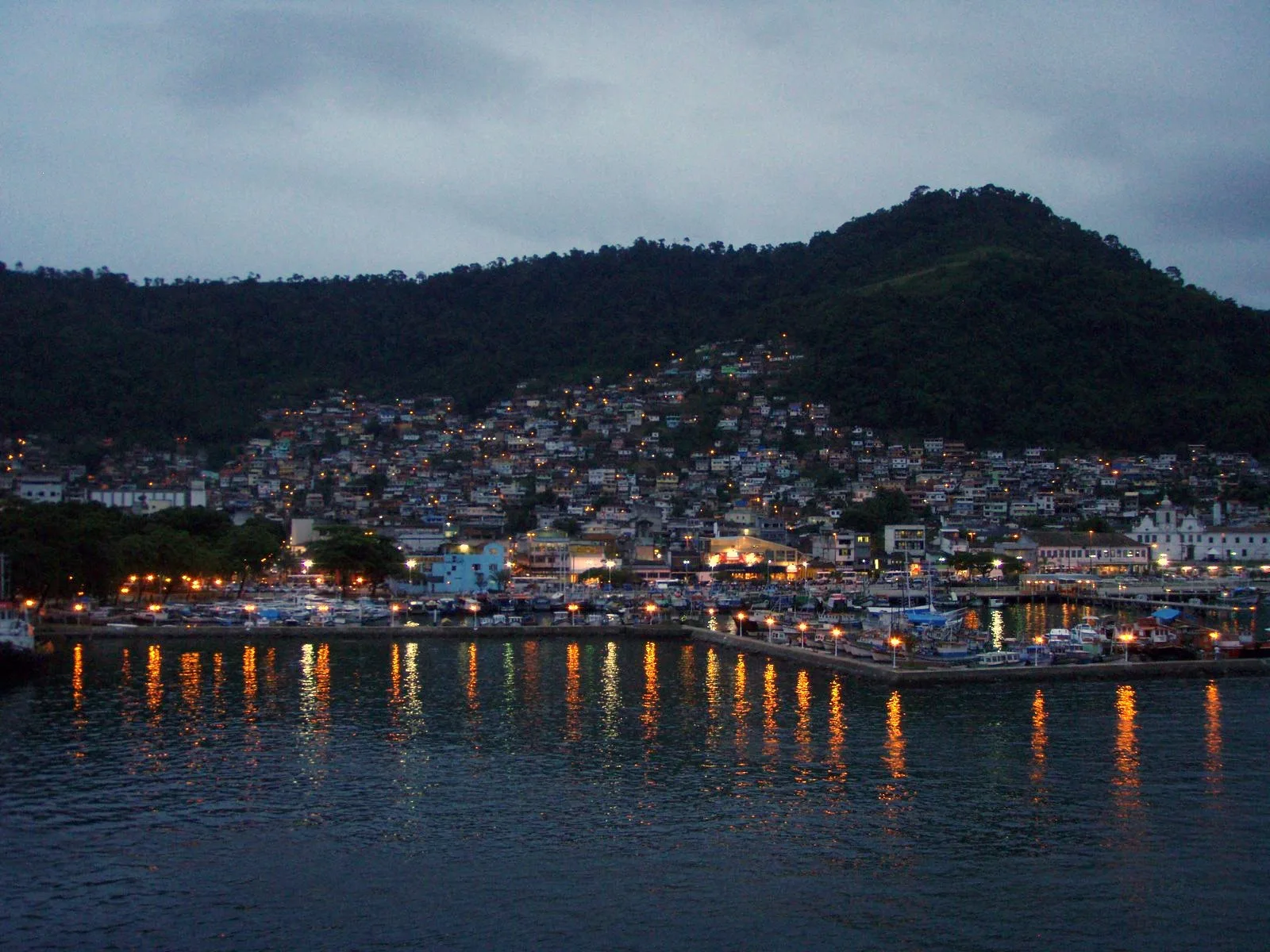 View of Angra dos Reis with calm sea, islands in the background, and boats along the coast.