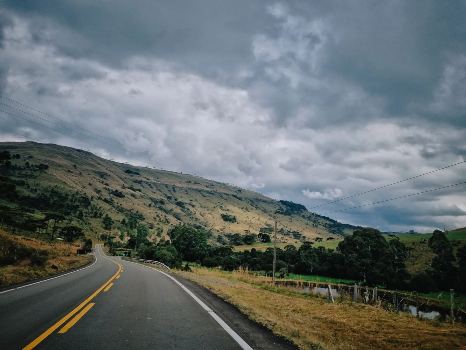 Camino de acceso en Urubici, con tramo rural y curvas entre montañas.