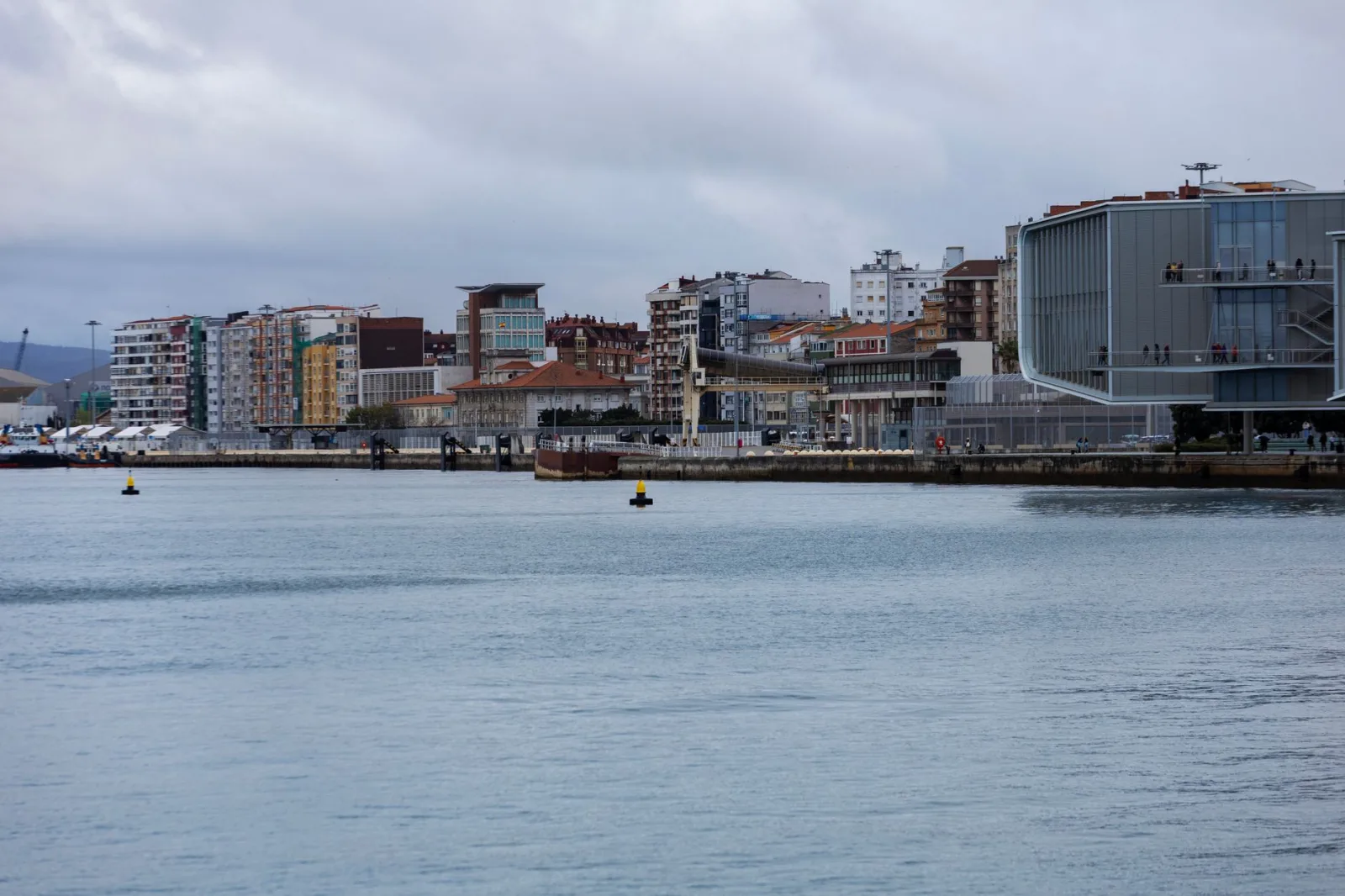Urban beach of Santander under a cloudy sky, with calm sea and a bustling waterfront.