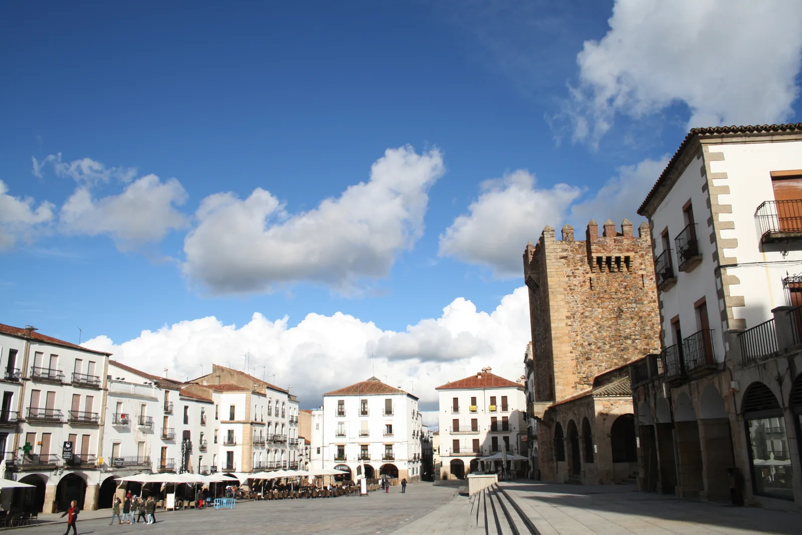 Vista da Plaza Mayor de Cáceres com muralhas medievais e torres históricas ao fundo