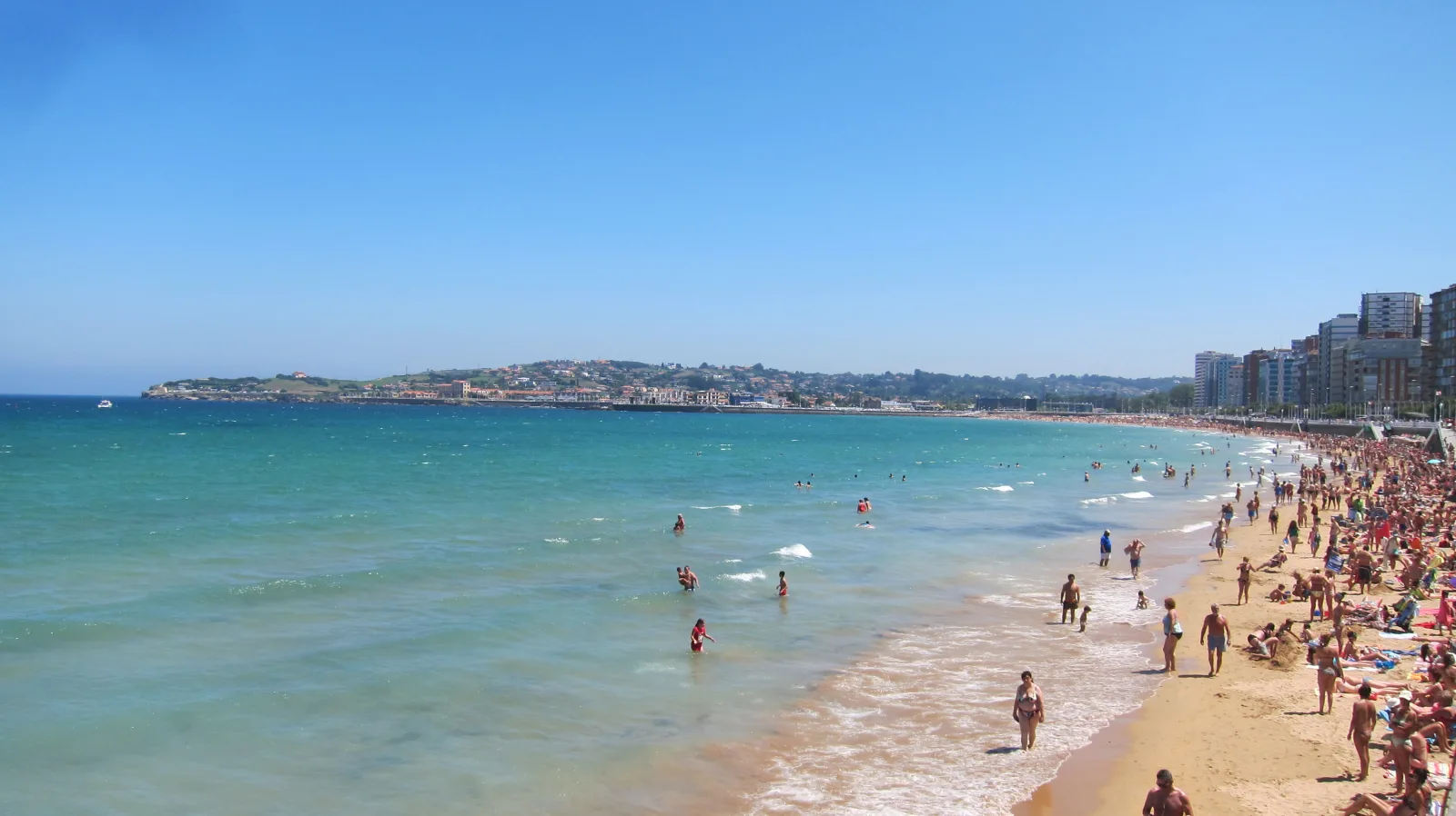 Gijón waterfront on a summer day, with clear skies and tourist activity.