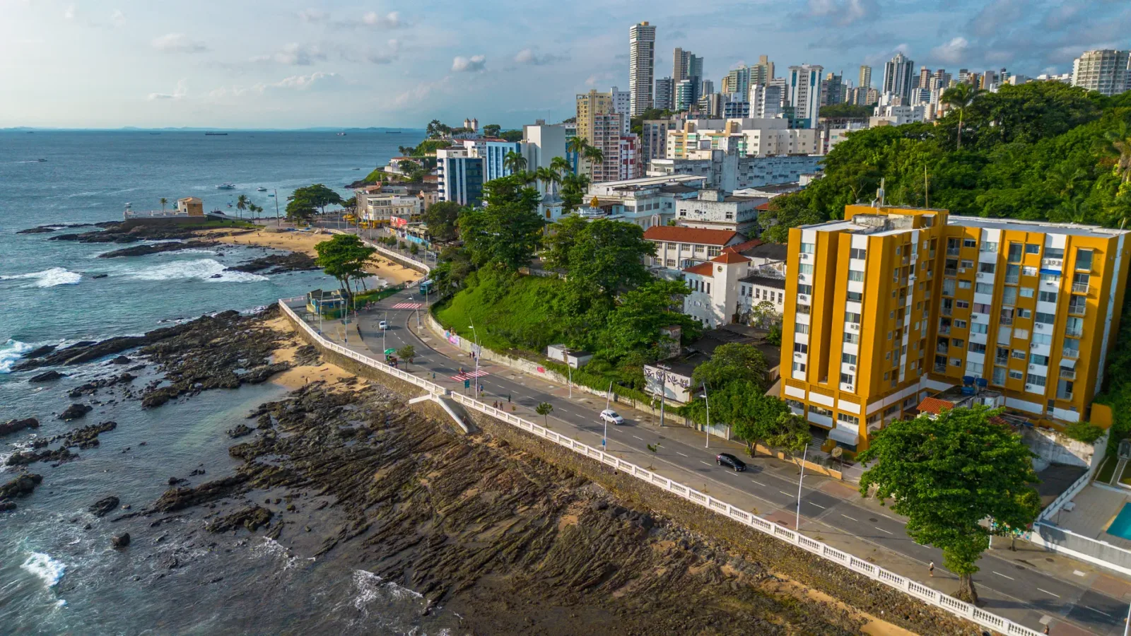 Car driving on a highway toward Salvador, with a coastal landscape in the background.