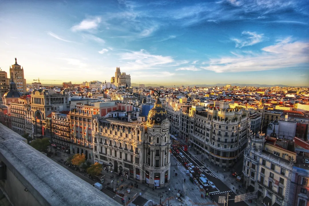 Rua central de Madrid com prédios históricos e movimento urbano ao anoitecer