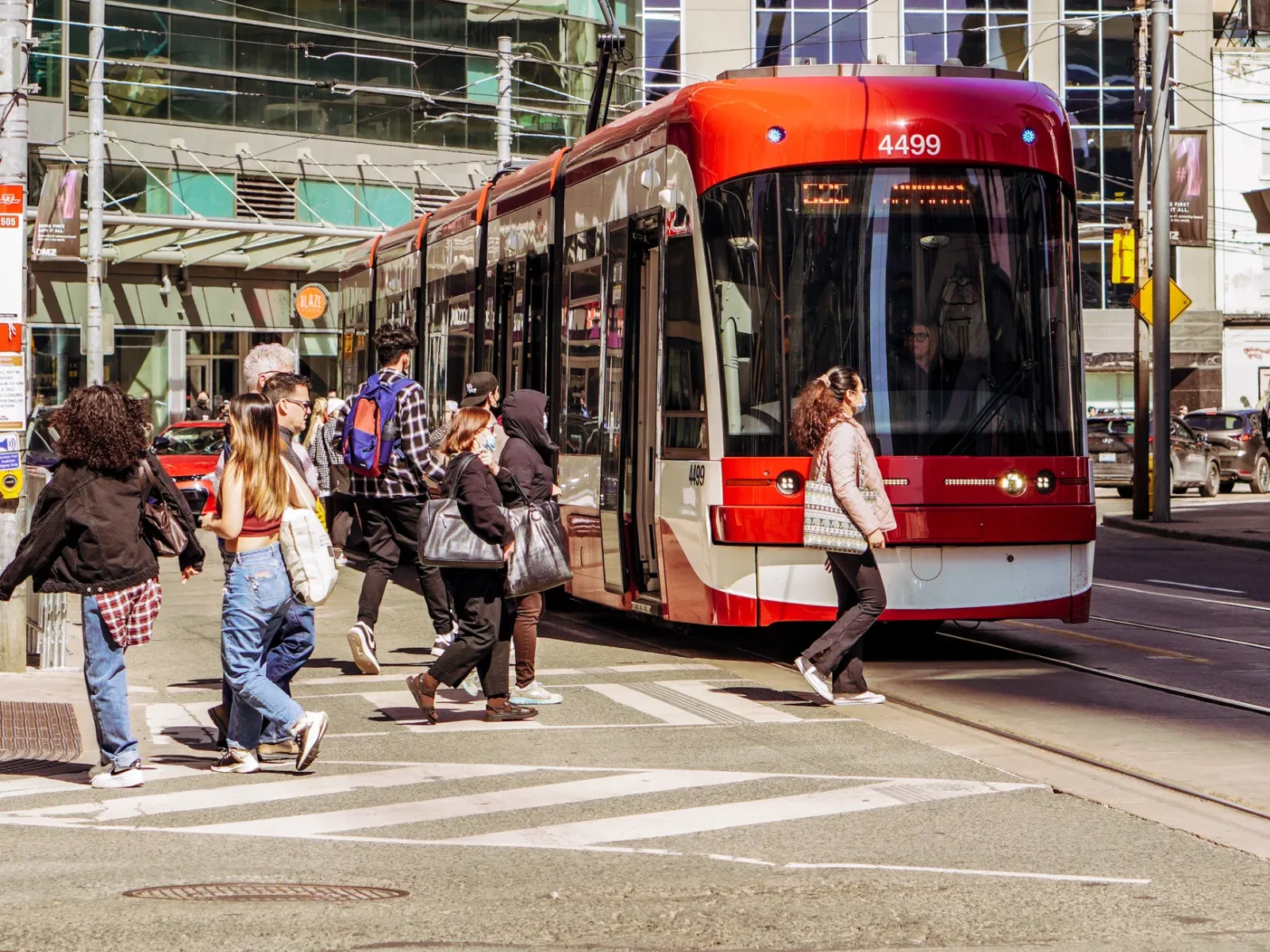 Streetcars and buses circulating in downtown Toronto, with tall buildings in the background.