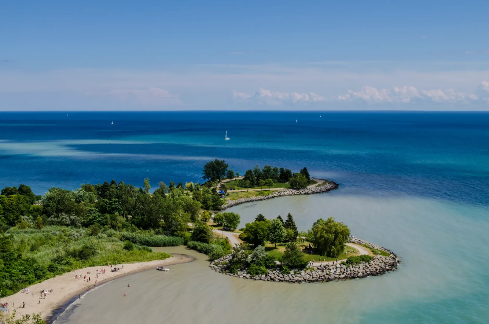 Cyclists and pedestrians on the Toronto Islands with the skyline in the background and the lake in the foreground