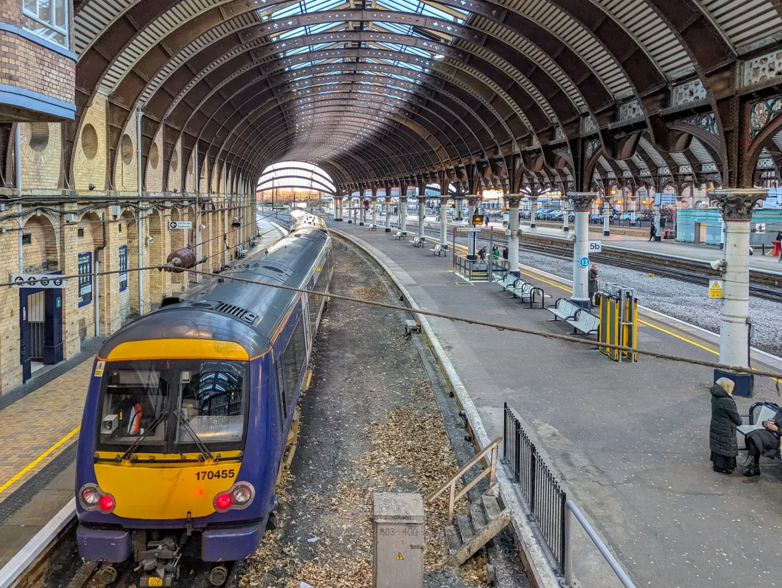 Estação de trem em York com passageiros chegando à cidade sob céu nublado.