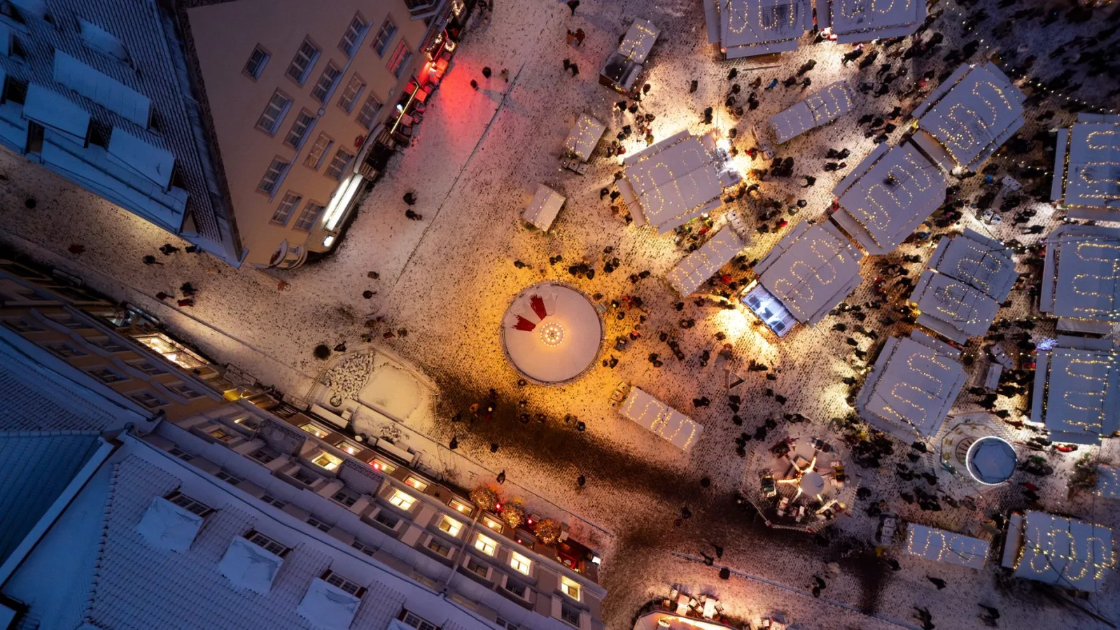 Rua de Tallinn coberta de neve, com clima invernal e luzes festivas ao fundo