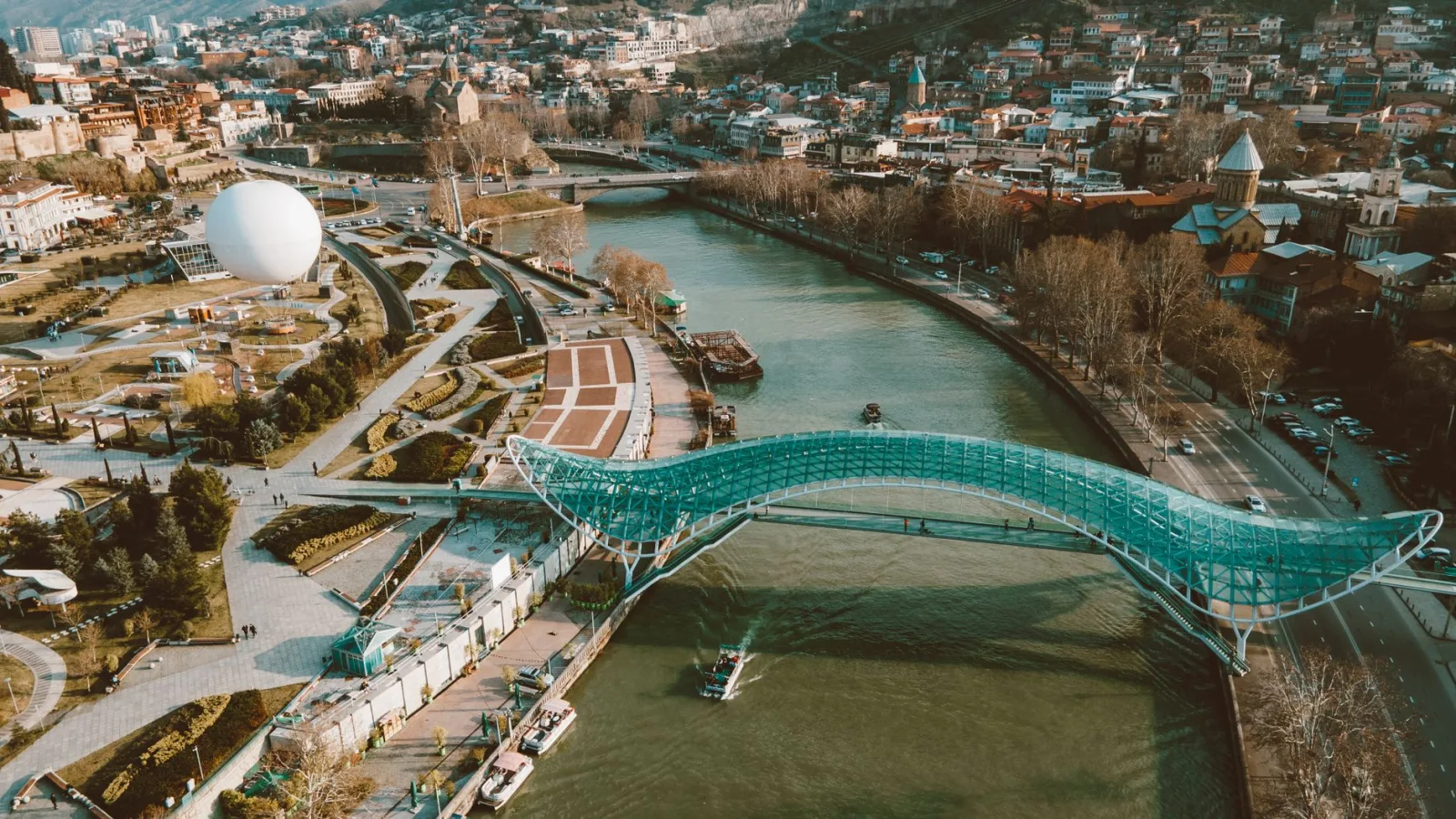 Vista panorámica de Tiflis al atardecer, con edificios históricos y colinas al fondo