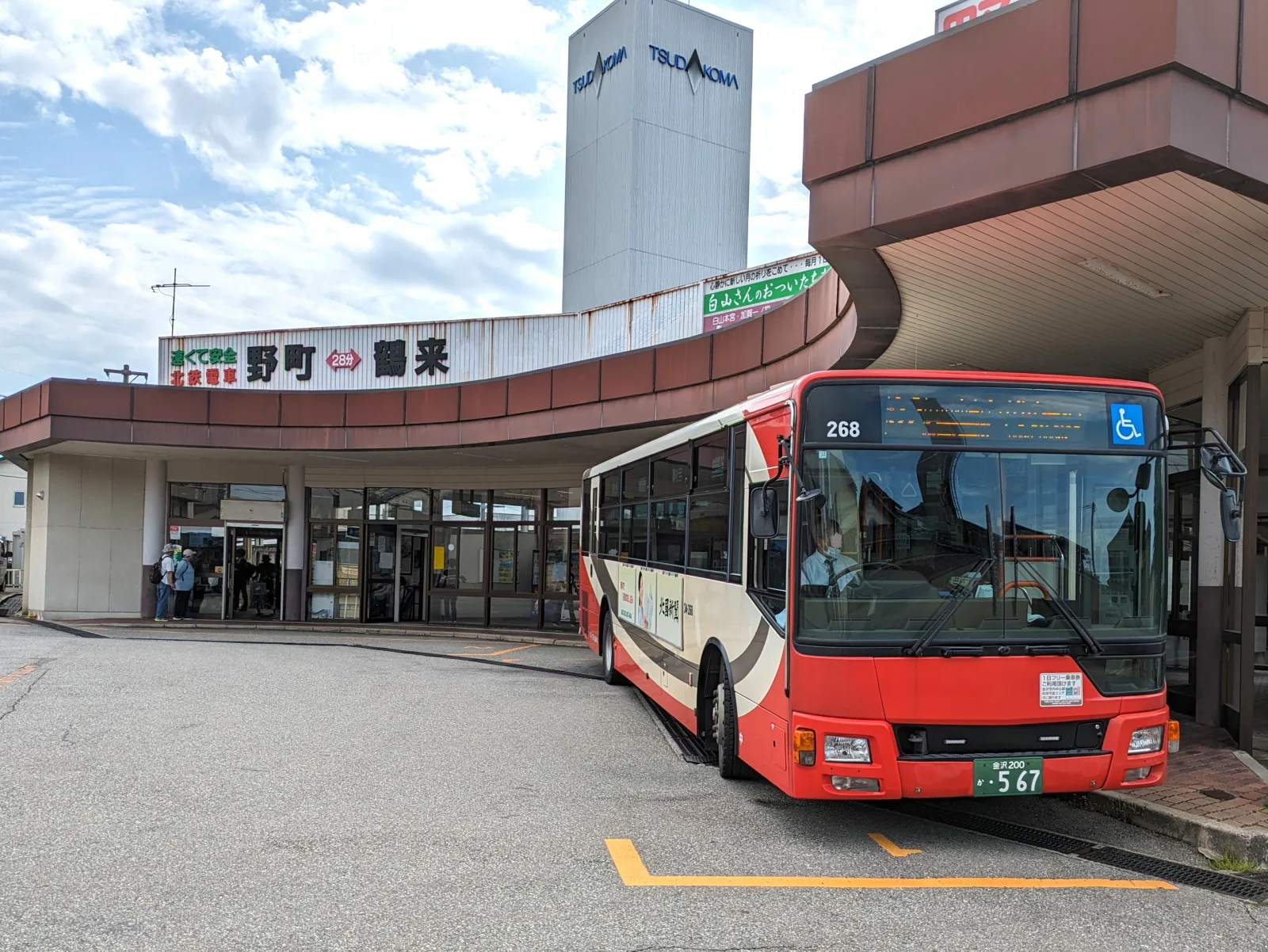 Rua compacta de Kanazawa com ônibus urbano e pedestres caminhando pela cidade