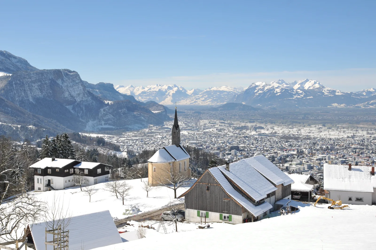 Vista de Dornbirn com montanhas, sugerindo trilhas e paisagens sazonais.