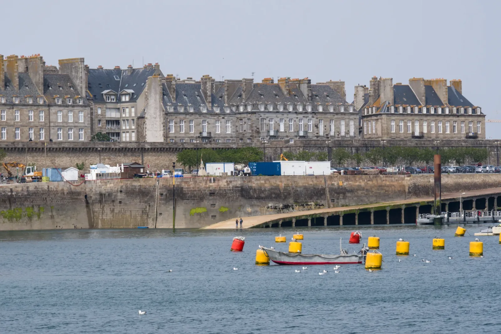 Stone walls and houses of Saint-Malo by the sea under clear skies.