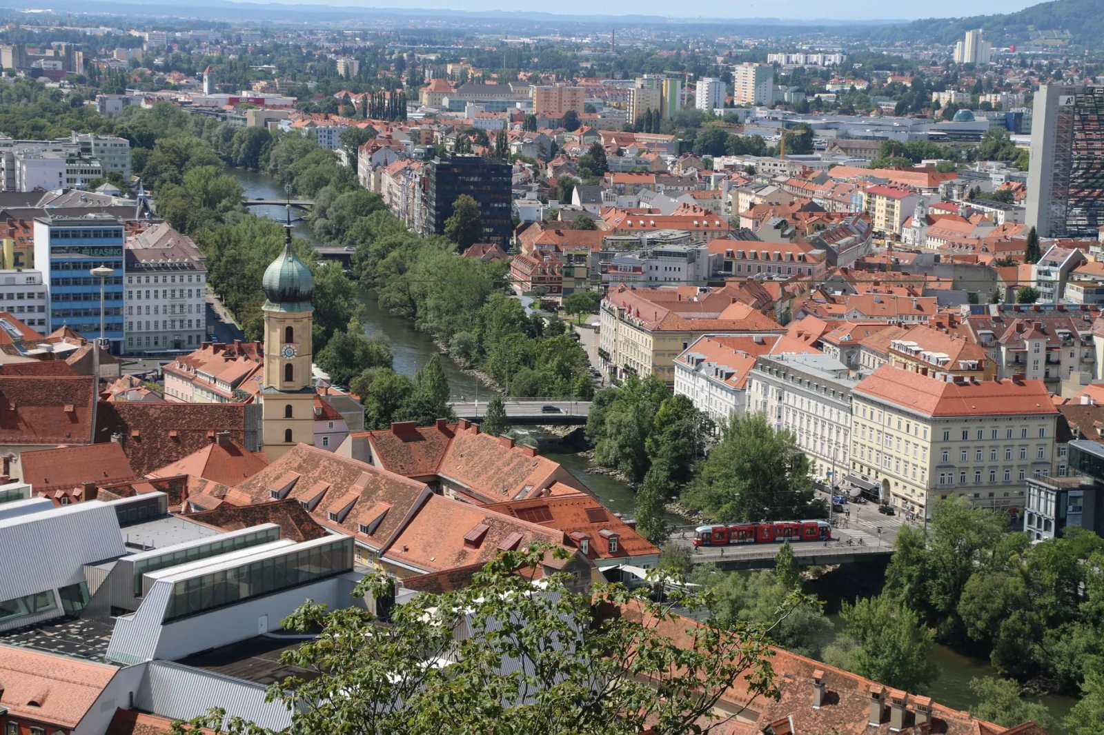 Centro histórico de Graz com prédios históricos e o Schlossberg ao fundo.