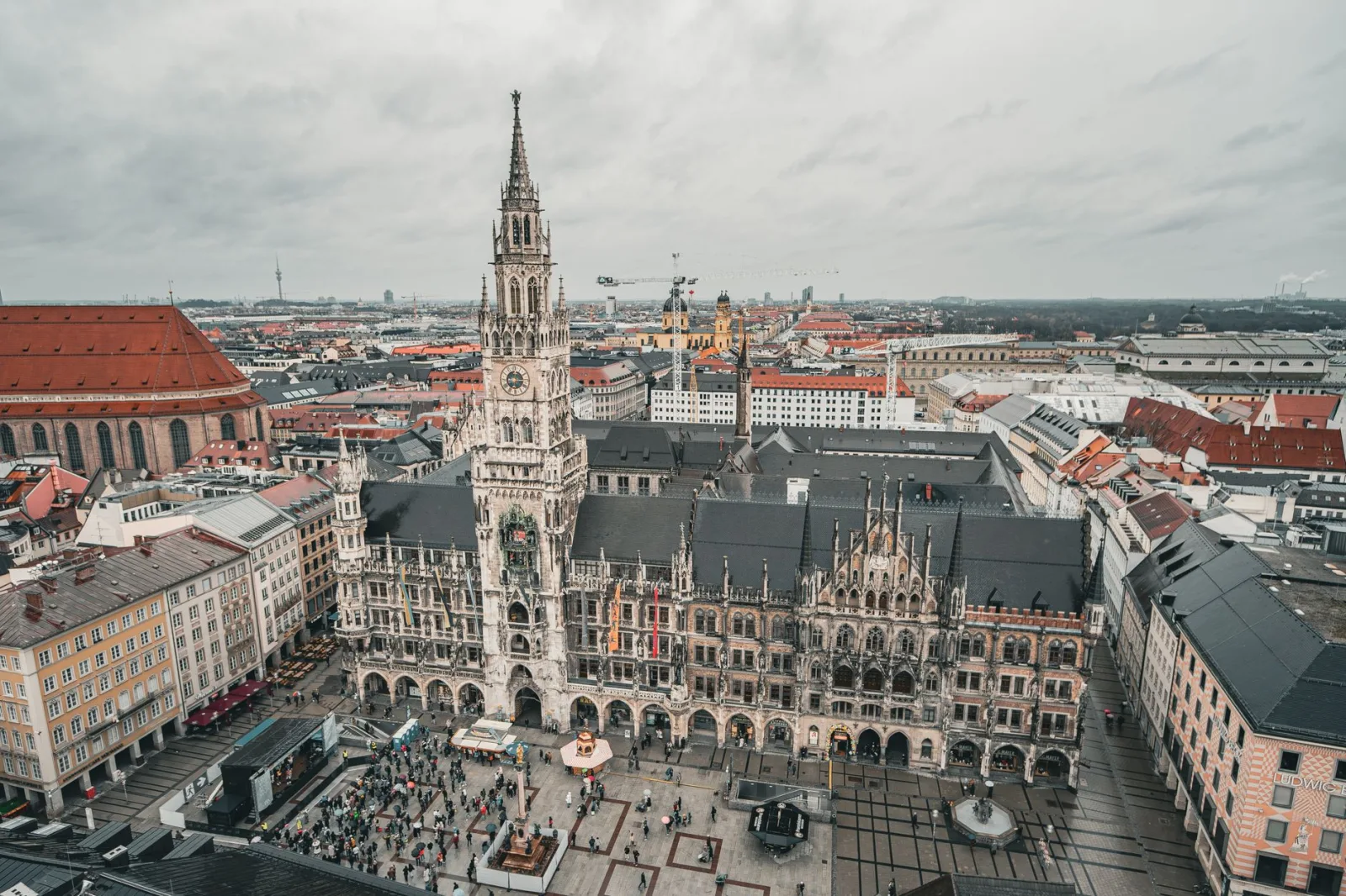 Trams and buses run along a street in downtown Munich, with historic buildings in the background.