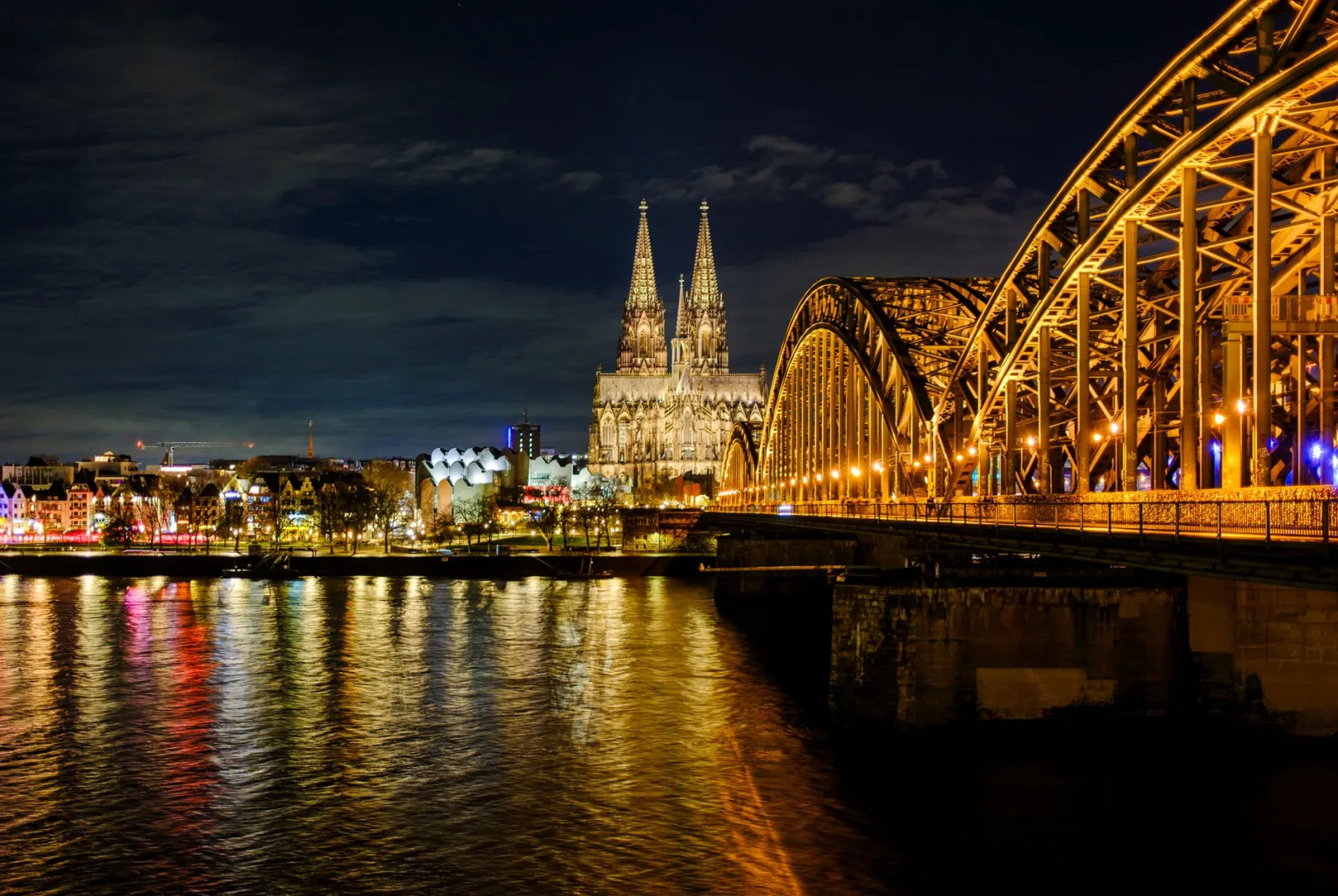Interior of Cologne Cathedral with tall stained-glass windows, Gothic arches, and soft light.