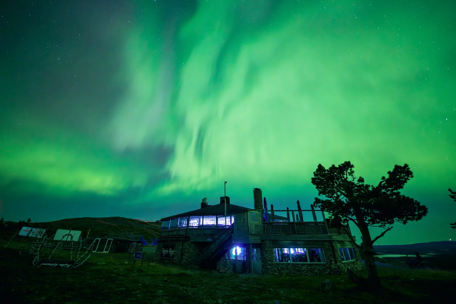 Aurora boreal iluminando o céu noturno de Levi sobre a paisagem nevada.