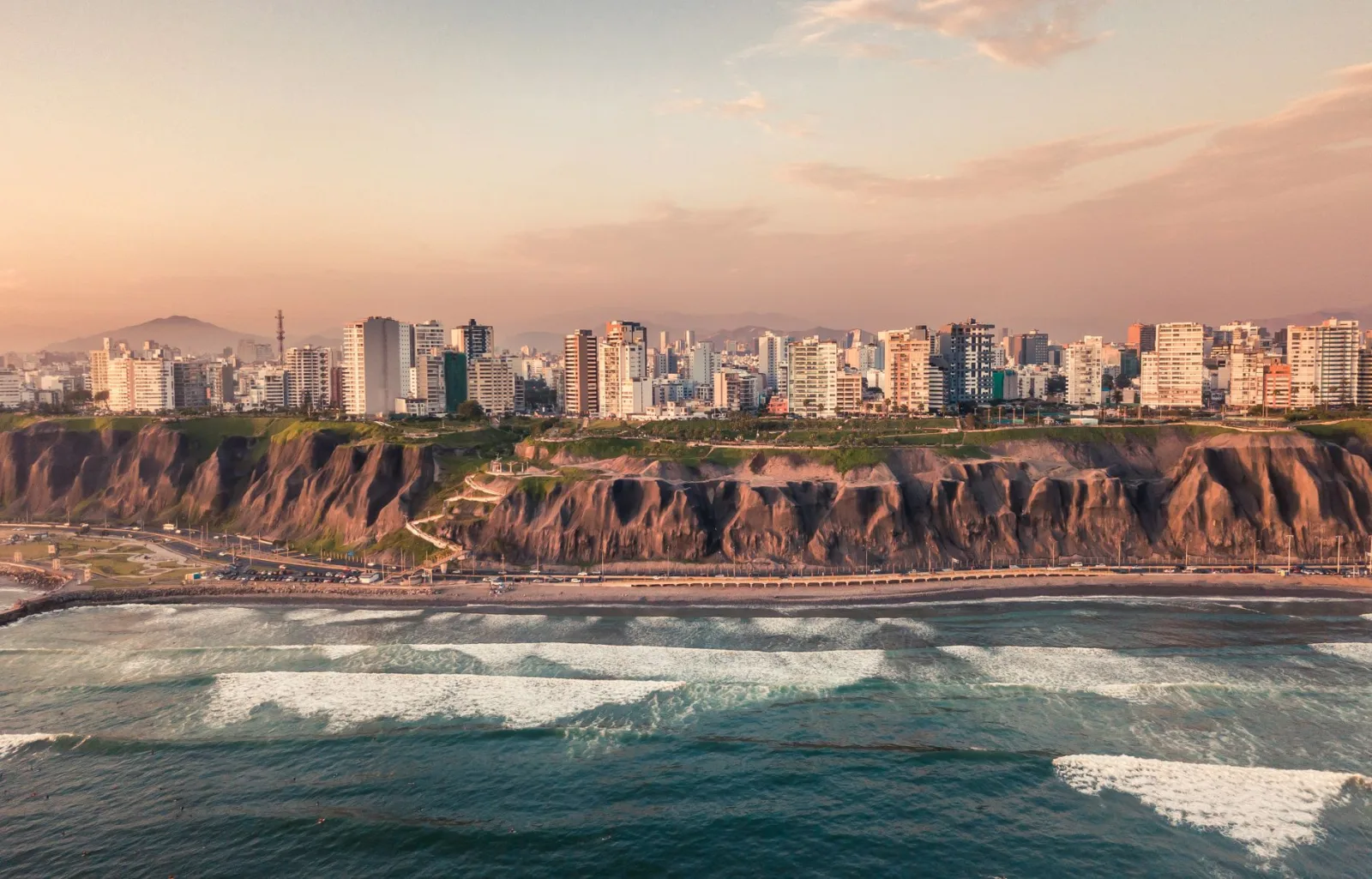 Vista panorámica de Lima con mar y edificios costeros al atardecer