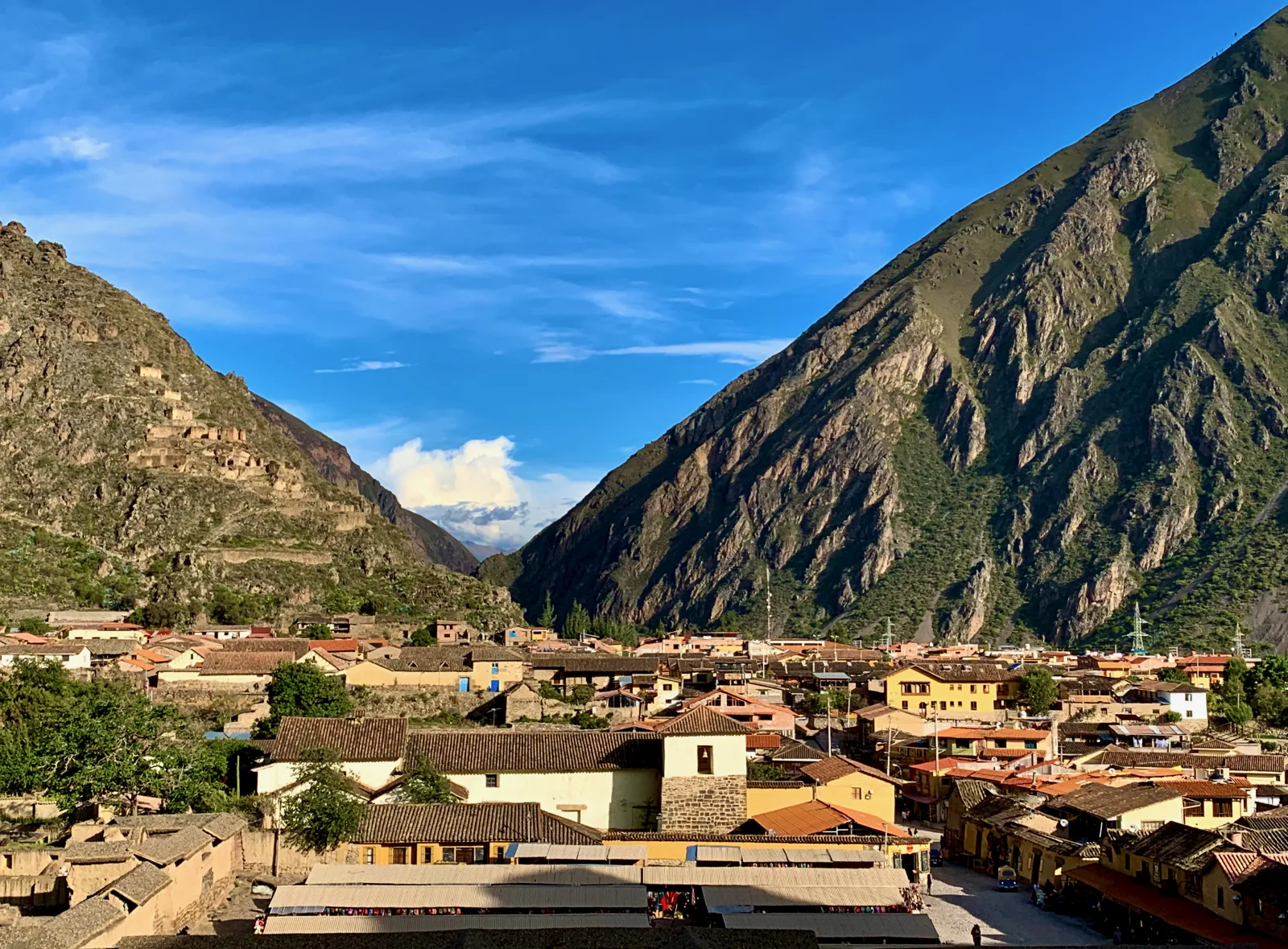 Stone street in Ollantaytambo with a water canal and activity in Plaza de Armas