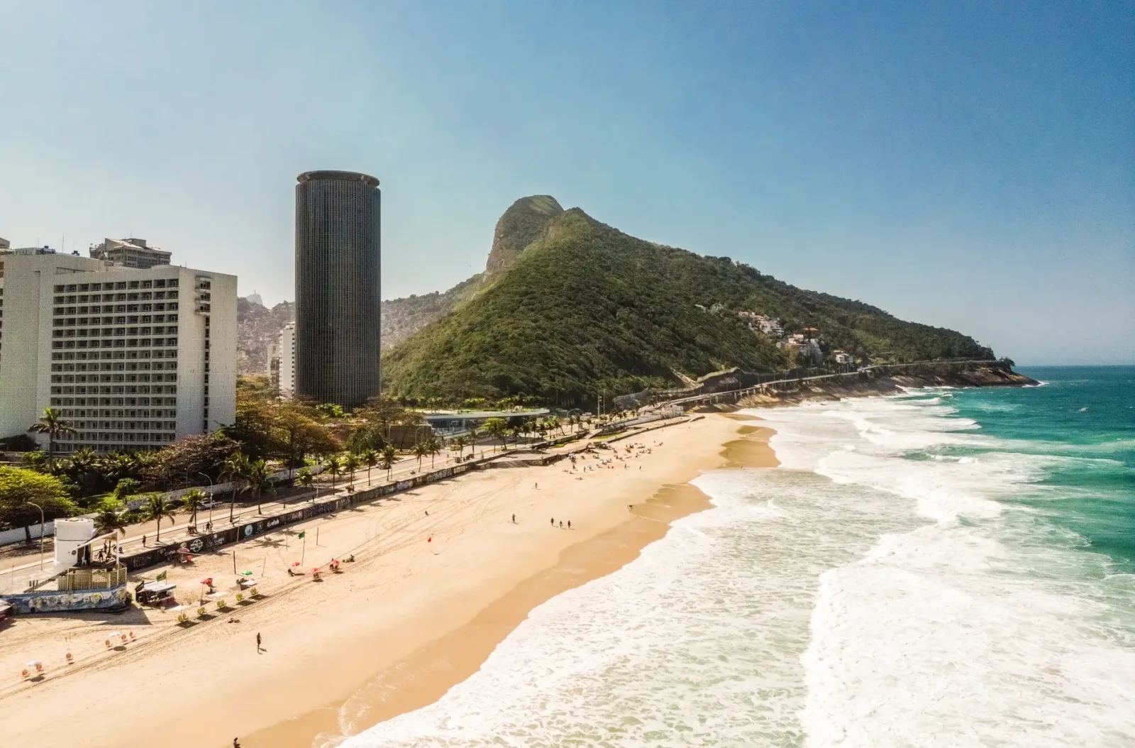 Vista panorâmica do Rio de Janeiro com praia, morros e áreas urbanas próximas.