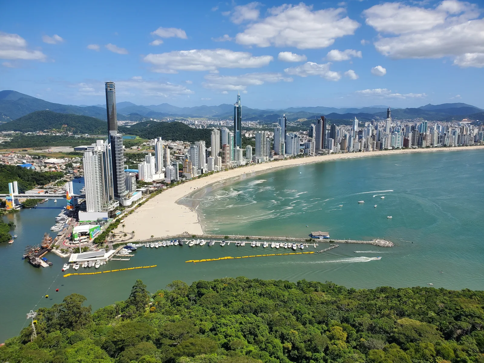 Orla de Balneário Camboriú com arranha-céus à beira-mar e praia movimentada.
