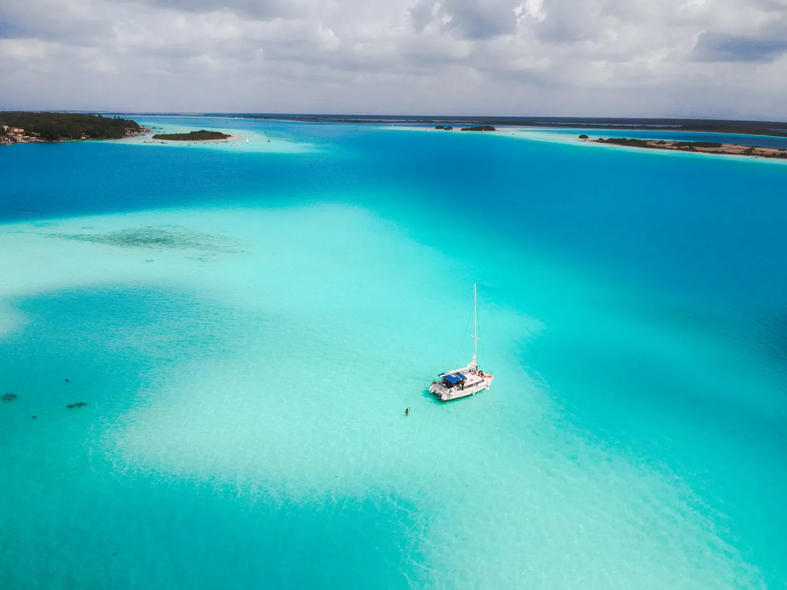 Vista de la laguna de Bacalar con aguas turquesa y un muelle a lo lejos.