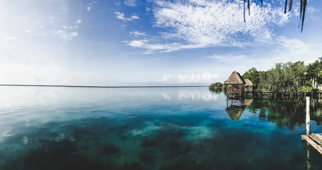 Cubierta de madera a orillas de la laguna de Bacalar, con aguas azul turquesa y área de descanso.