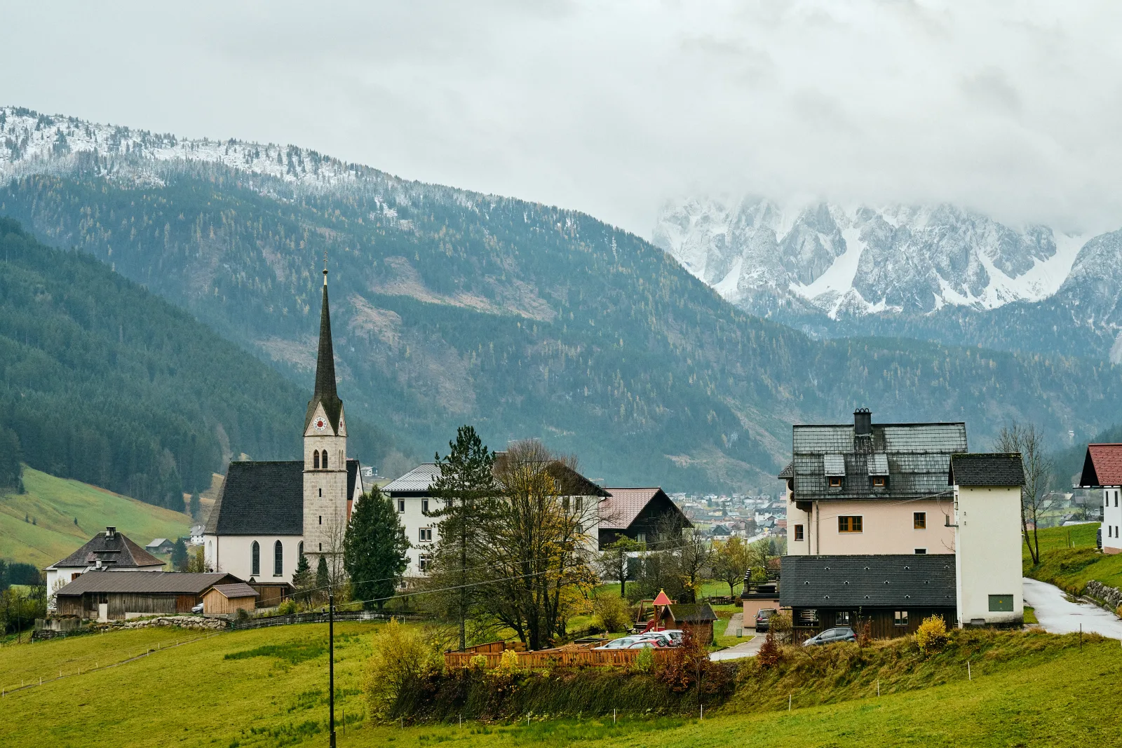 Vista de alojamiento alpino en Gosau, con un chalet y montañas al fondo.