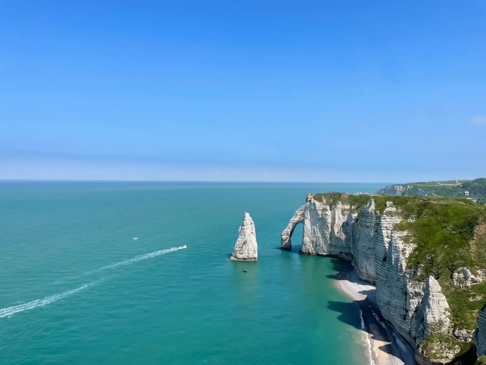 Falésias brancas de Étretat sobre a praia de cascalhos na costa da Normandia