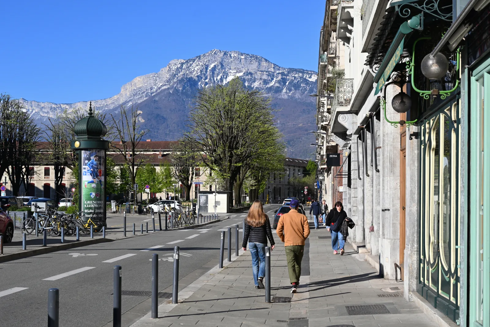 Grenoble sob sol, com Alpes ao fundo e clima de inverno com neve nas montanhas.