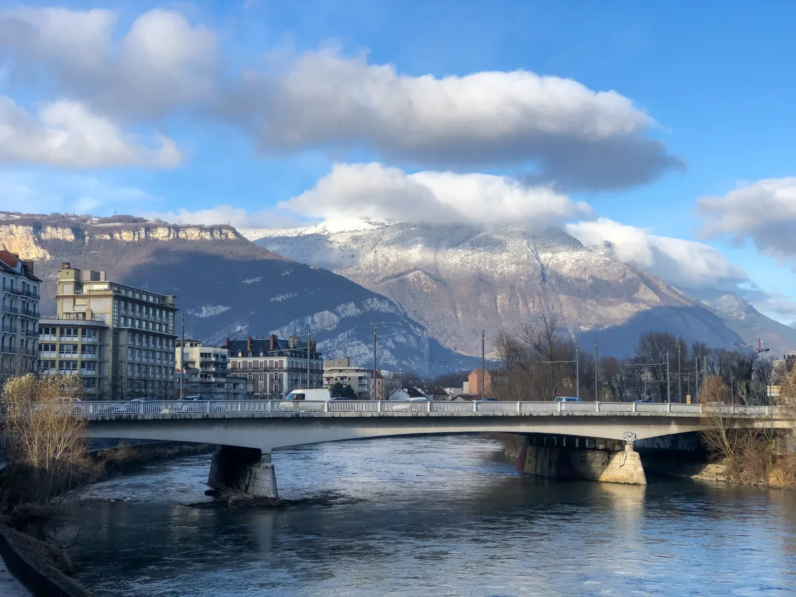 Rua estreita no centro de Grenoble, com praças históricas e lojas para passeio a pé.